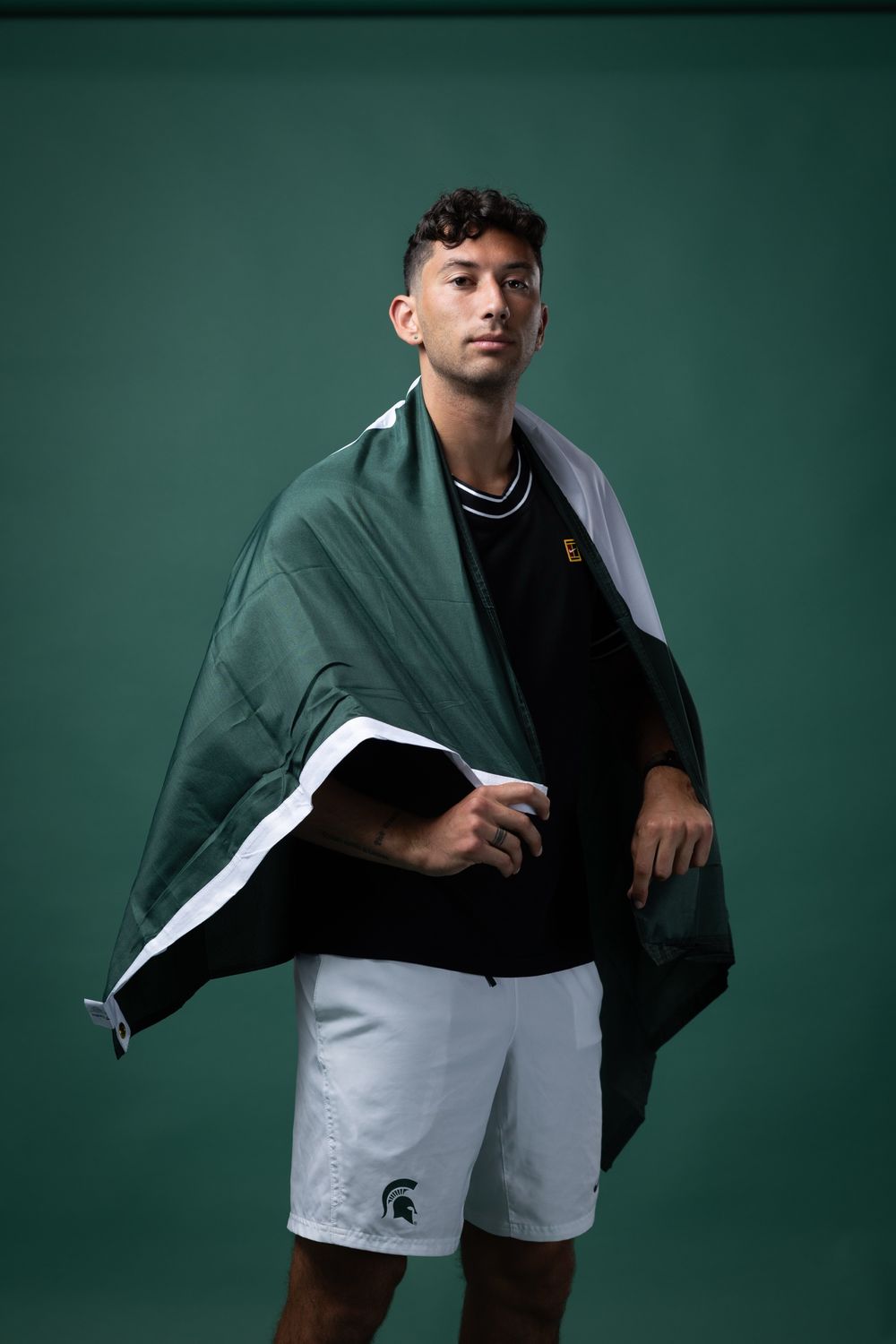 Portrait of Ozan Baris wearing a Michigan State flag